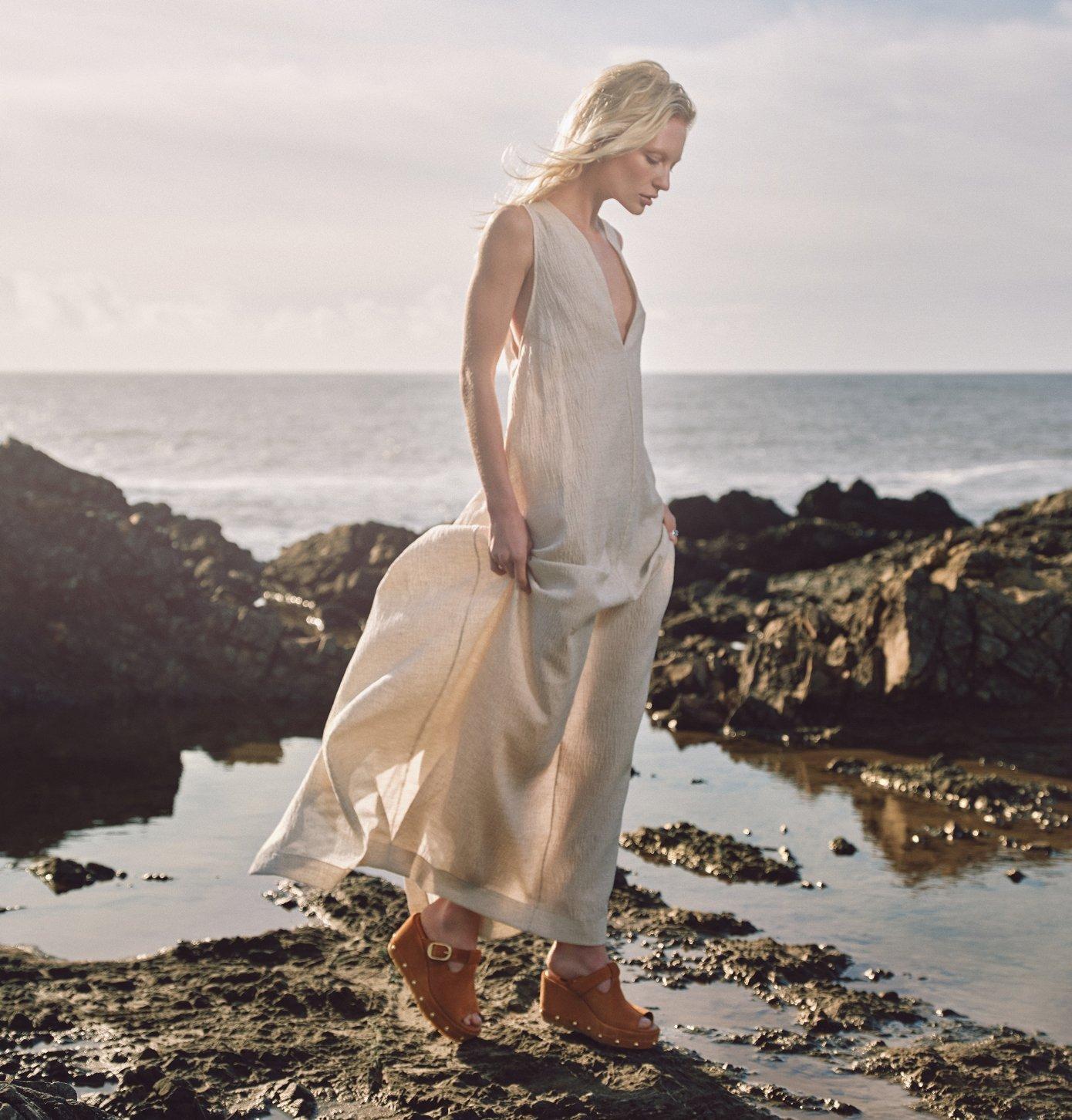 woman standing on a beach wearing sorel sunpeak wedge rvt sandals