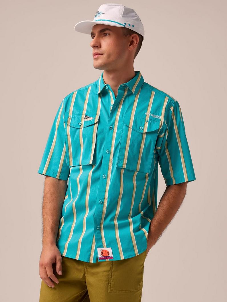 Man wearing turquoise and yellow striped short-sleeve button-up shirt with chest pockets and white cap.