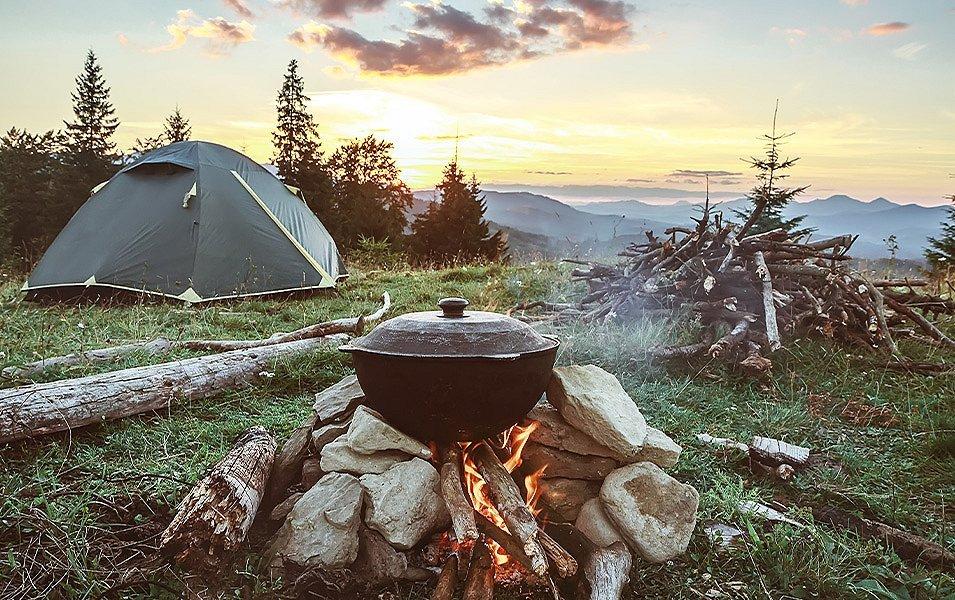 A hiker has set up a smart camp, with a tent that's perfectly staked out, and far enough from the campfire for safety.