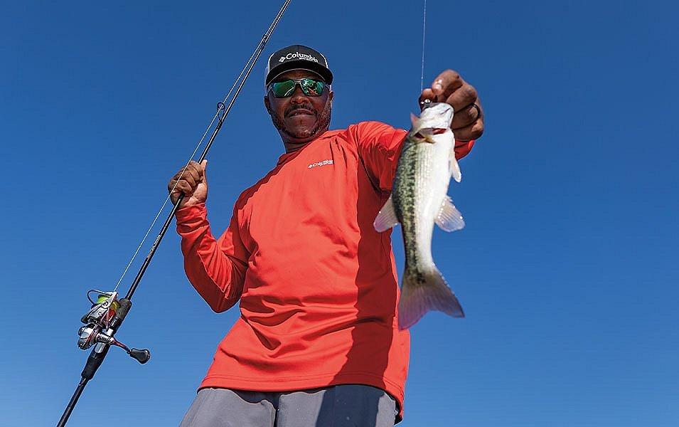 Pro angler Mark Daniels Jr. holds a fish for the camera and smiles. 