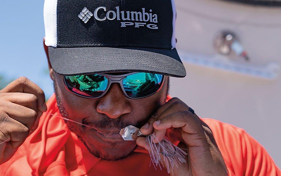 Pro angler Mark Daniels Jr. ties a fishing knot with a piece of bait. 