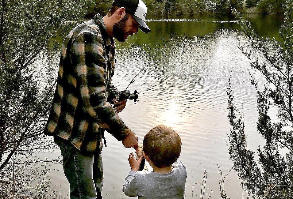 Father and son fishing by a river. 