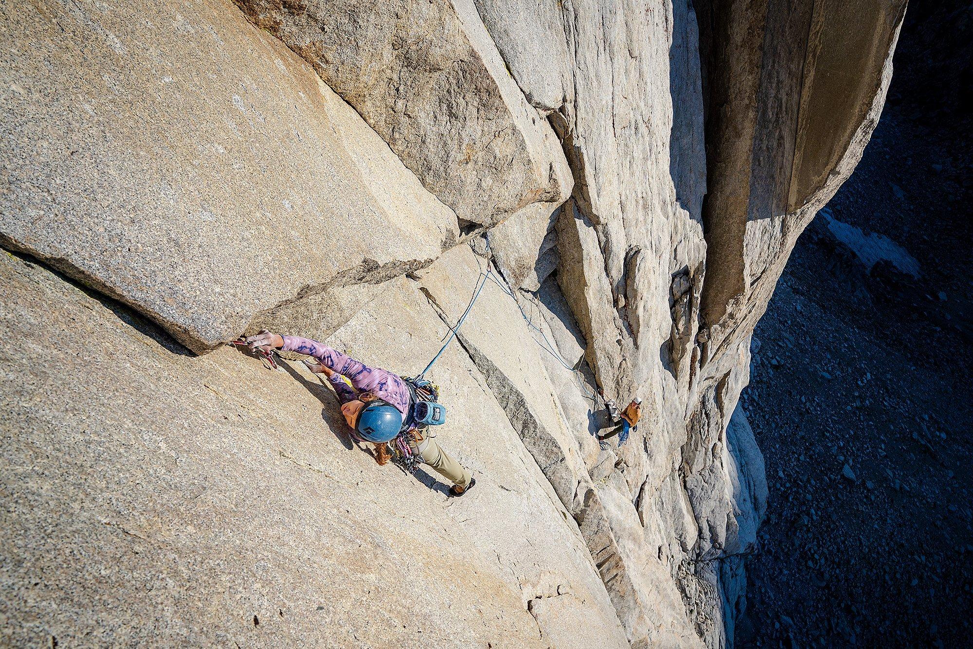 Jen reaches for her next hold while Casey belays below.
