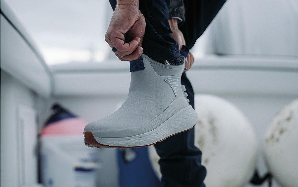 Using the fore and aft pull tabs, a man slips his foot into his stylish deck boots. 