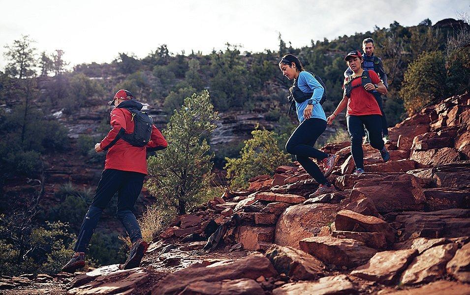 Four trail runners running down a rocky hill. 