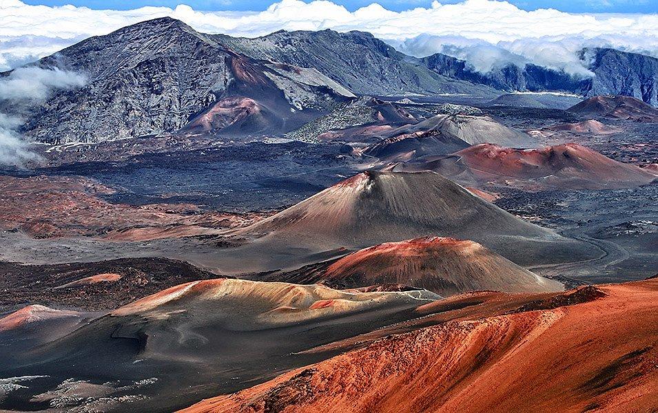 High above the cloudbank, the rich earthtones of a volcanic landscape stretches out in Haleakalā National Park. 
