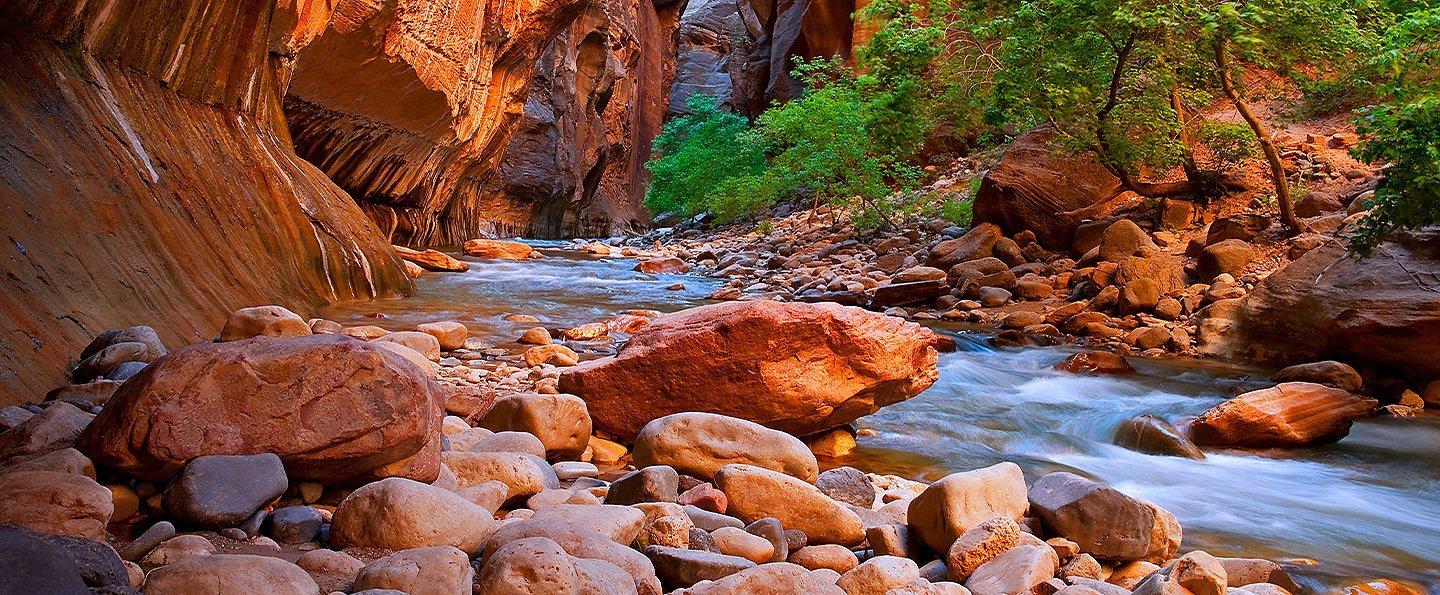 Dramatic sandstone cliffs sweep down to a bubbling brook. 