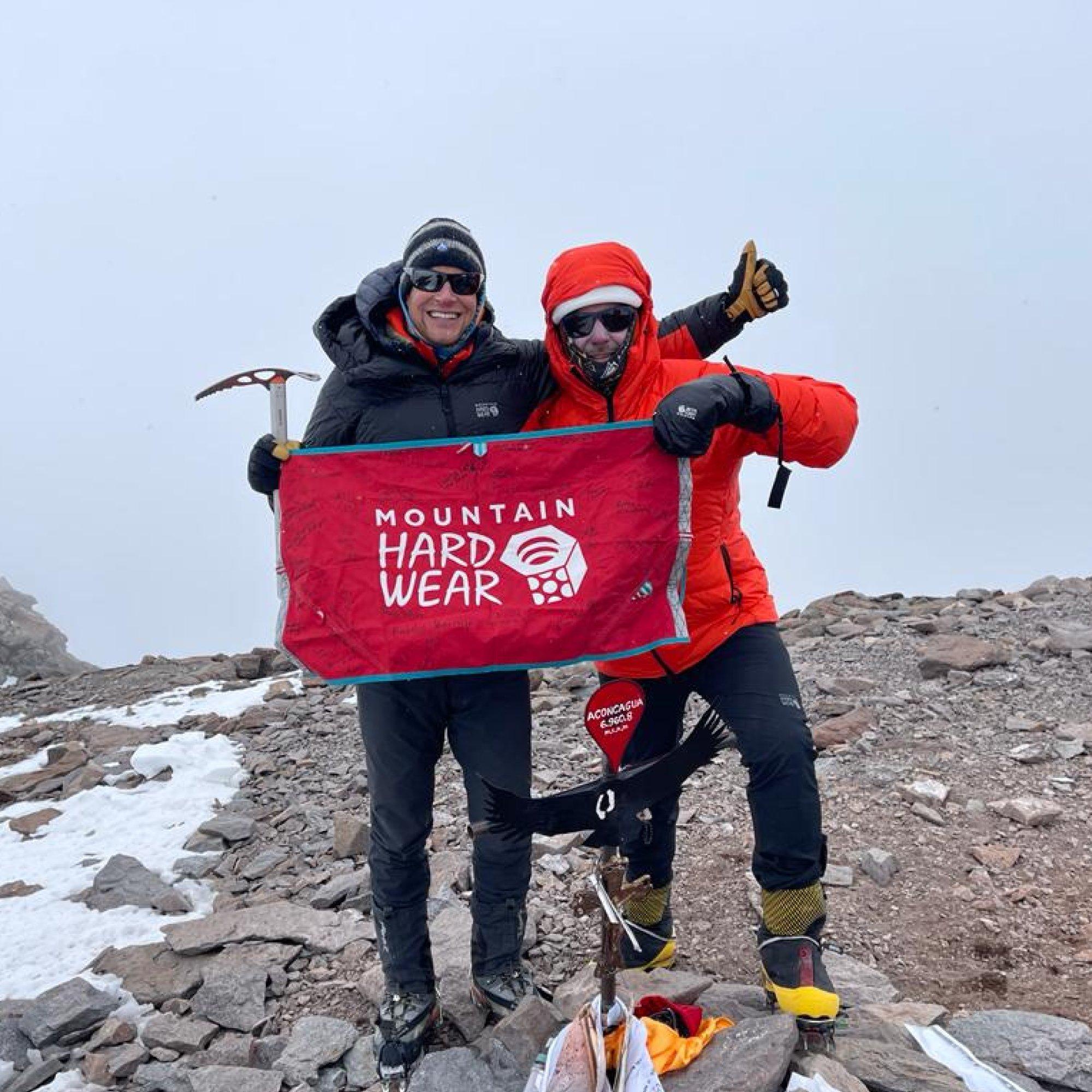 Beaming out from zipped plush, down hoods, professional AMGA guide Garret Madison celebrates with a fellow mountaineer.