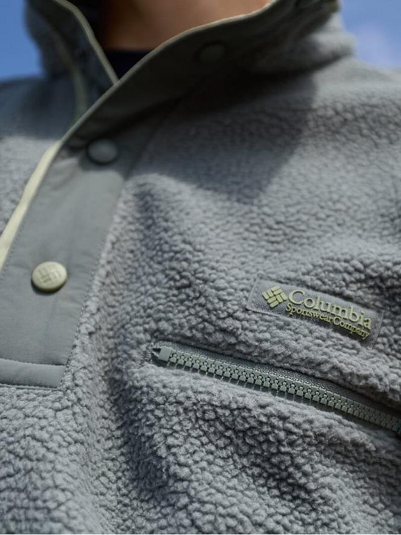 Close-up of gray fleece jacket with snap buttons and zippered chest pocket being worn.