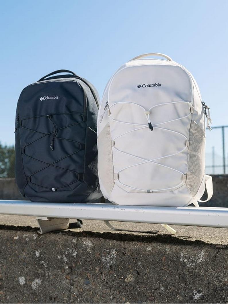 Two backpacks with bungee cord lacing systems displayed side by side, one in navy blue and one in cream.