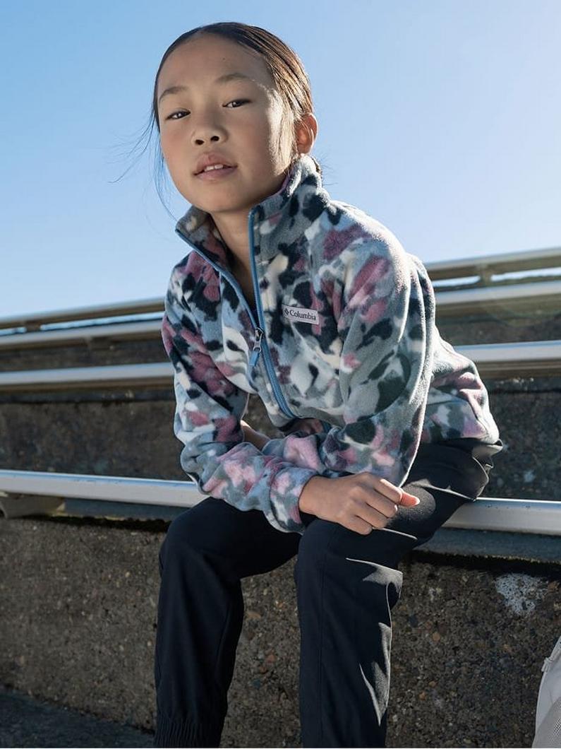 Child sitting outdoors wearing a floral print fleece pullover with quarter-zip and black pants.