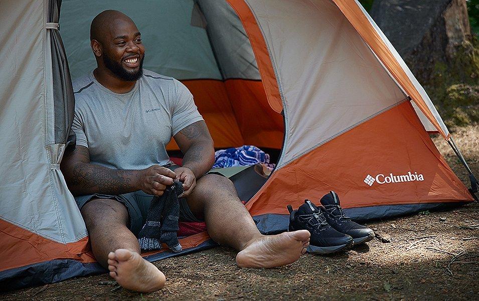 Man sitting in Columbia Tent putting on socks and Columbia hiking shoes.