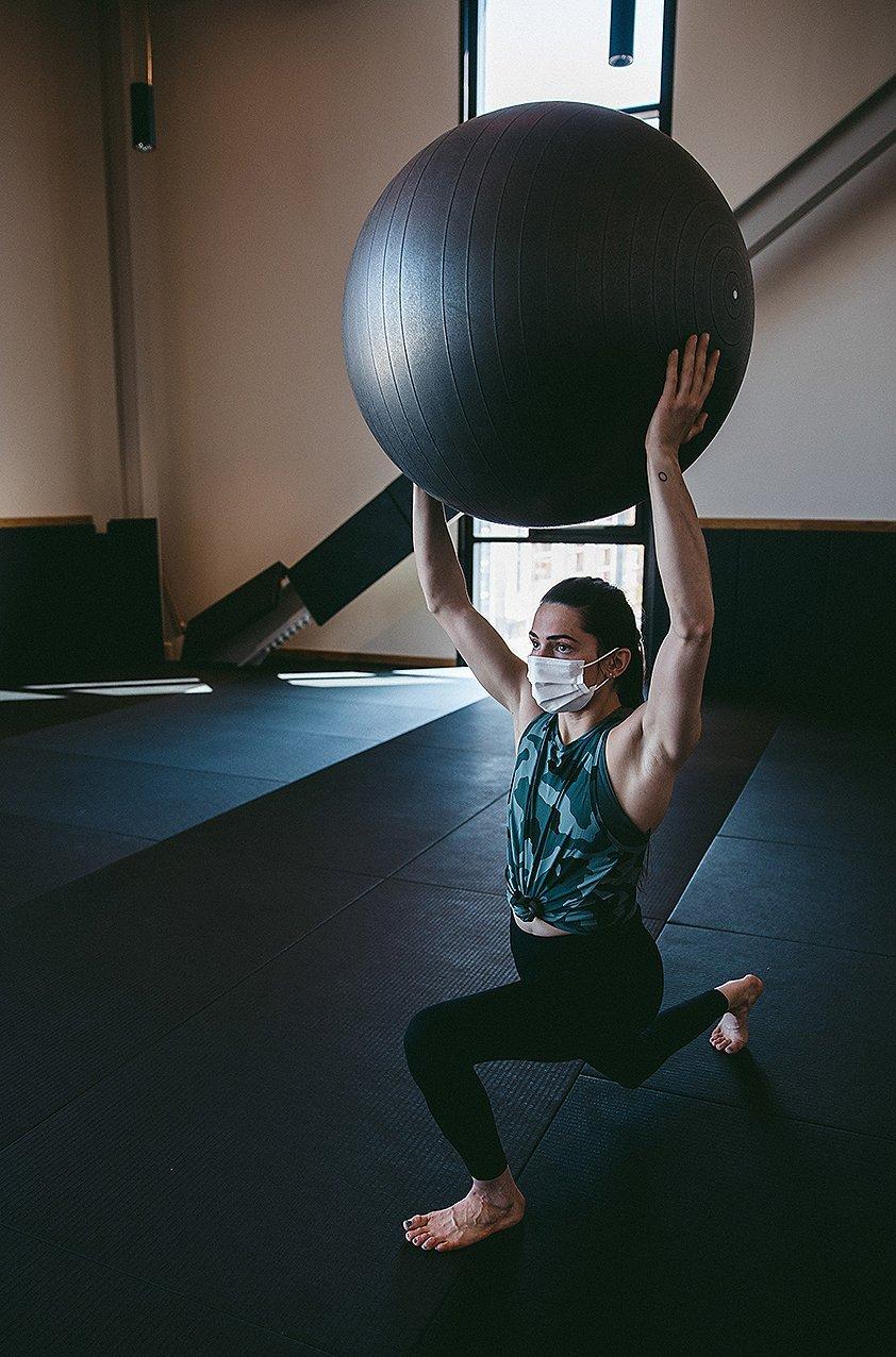 Kyra lifting a big exercise ball overhead