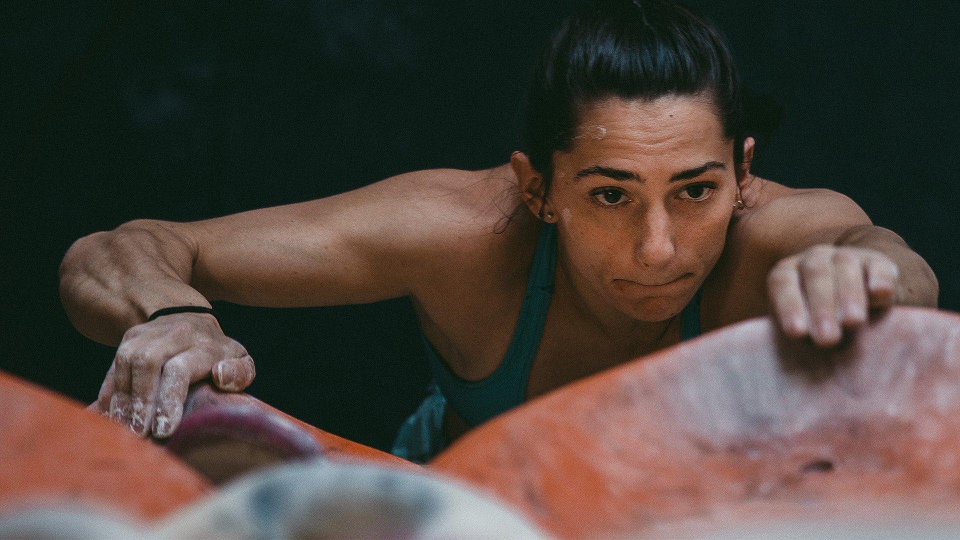 MHW Athlete Kyra Condie boulders, reaching for her next hold