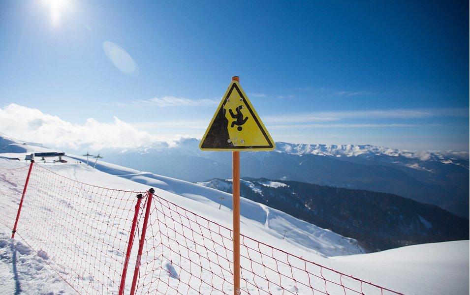 A sign at a ski area, depicting a person tumbling upside down, warns of danger when skiing out of bounds.