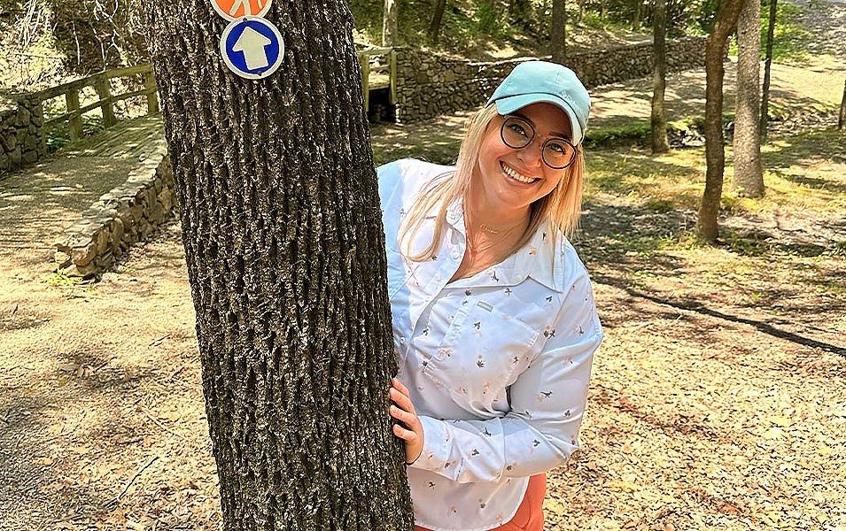 Chelsea McCurdy smiles at the camera wearing Columbia Sportswear’s Leslie Falls™ plus-size hiking shirt.