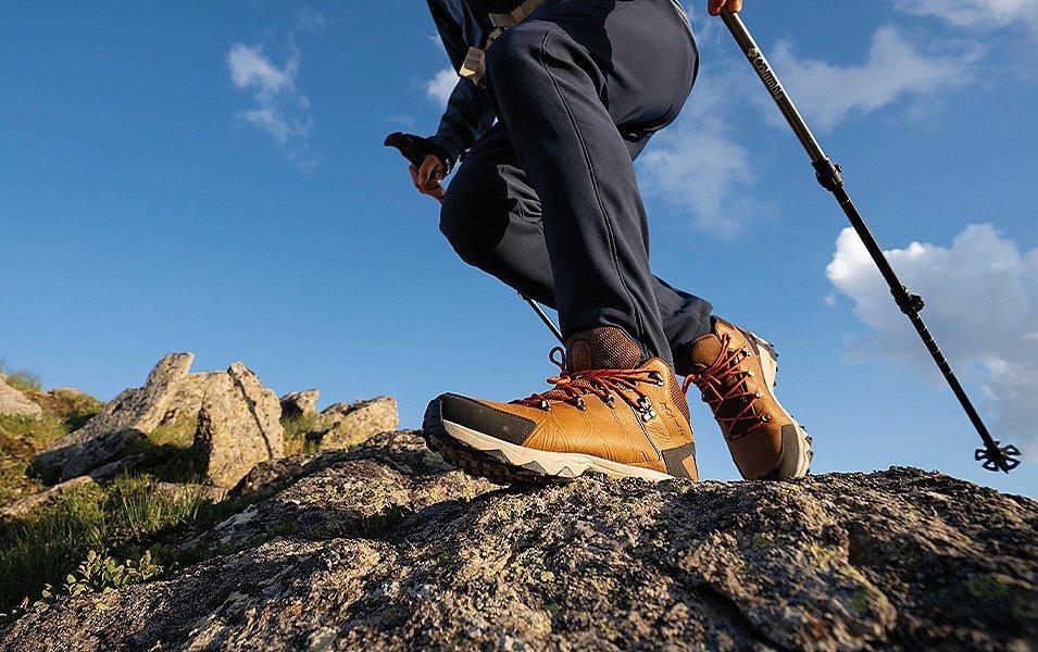 Legs of a hiker in Columbia Sportswear hiking boots walking over a rocky hilltop.