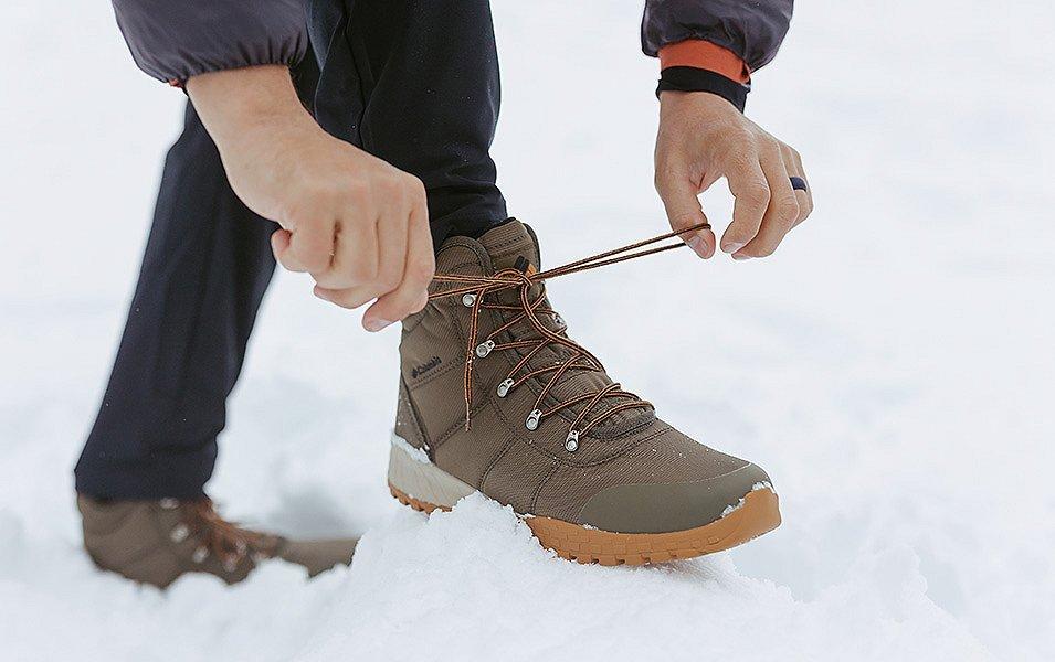 Hiker lacing Columbia Sportswear boots in the snow. 