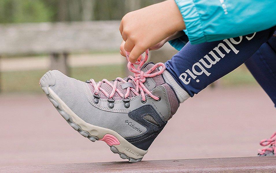 A person adjusting the laces on a Columbia Sportswear Hiking boot.