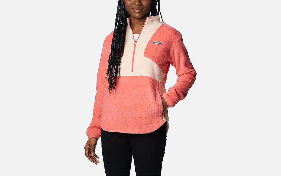 A product shot of a woman wearing a pink-and-white Columbia Sportswear fleece midlayer  set against a white background.
