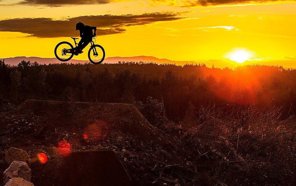 Biker jumping off a ramp at sunset. 