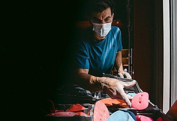 Josh Larson looking at gym climbing holds in dramatic lighting