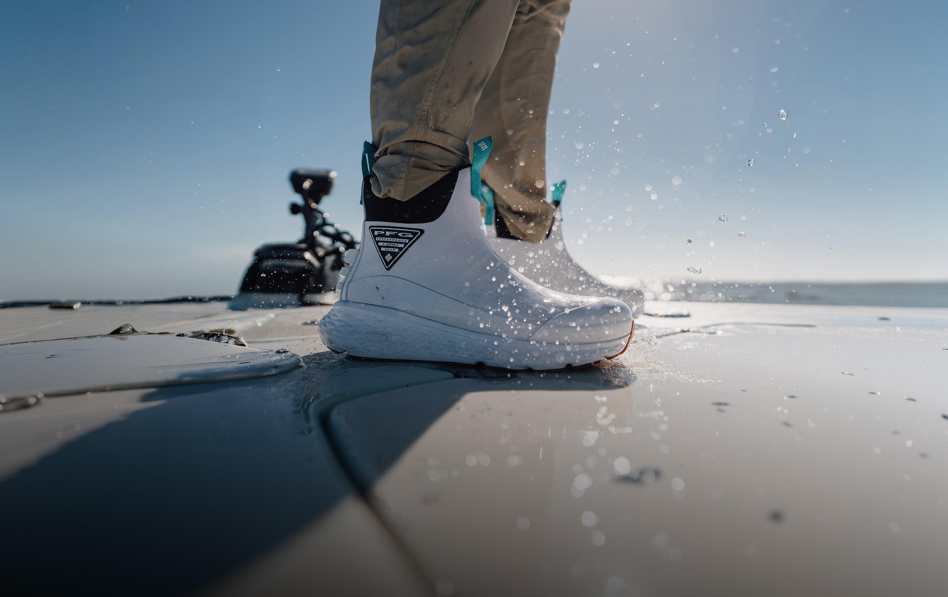 Person wearing white waterproof boots with turquoise laces stepping in shallow water on a dock.