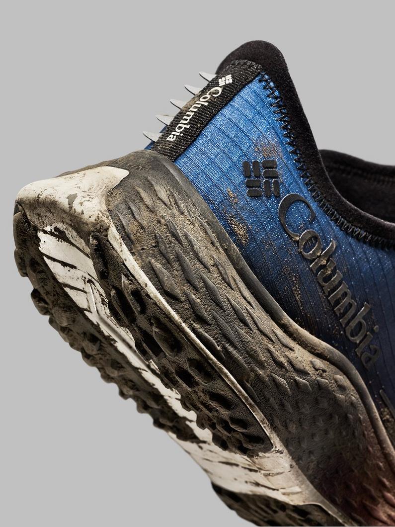 Well-worn blue and black athletic shoe showing muddy treaded sole and textile upper.