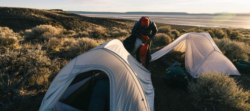 Two Nimbus tents set up on a backpacking trip by a lake in the distance.