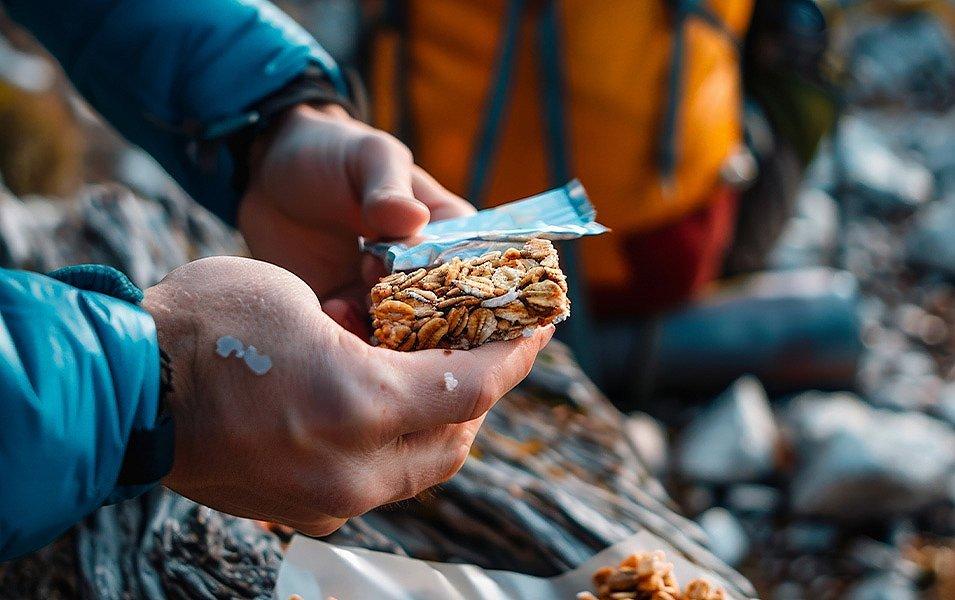 A person clutches a square bar of granola.
