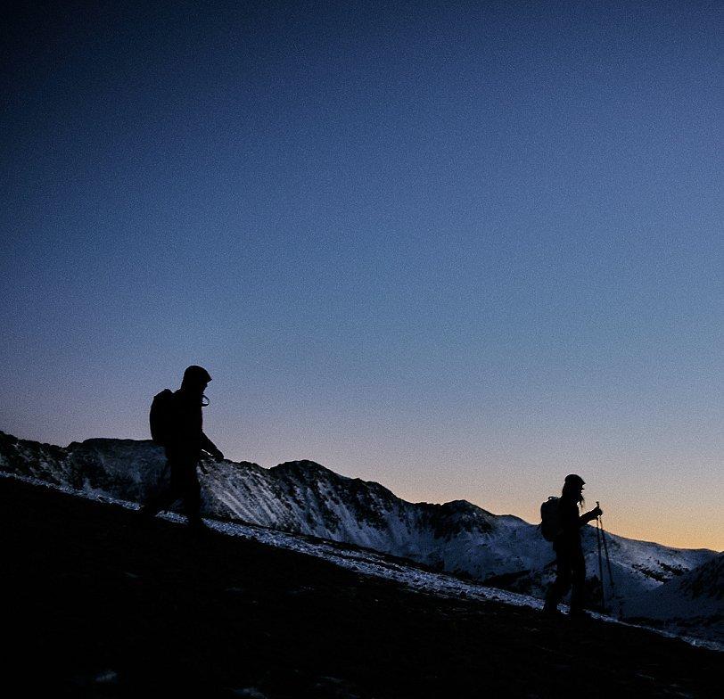 Two trail runners running through the mountains at sunrise.