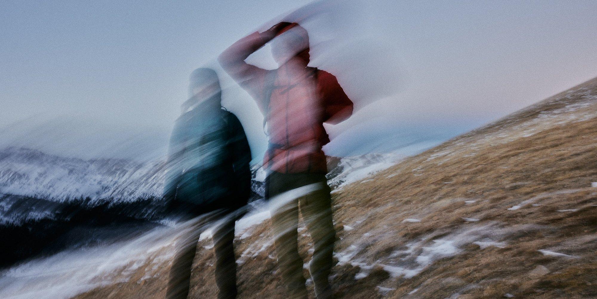 Hiking in cold weather, some snow in the background.
