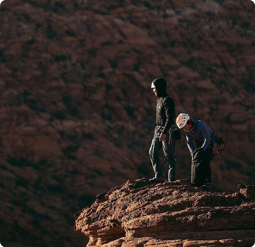 Two climbers in the sun at the top of their climb