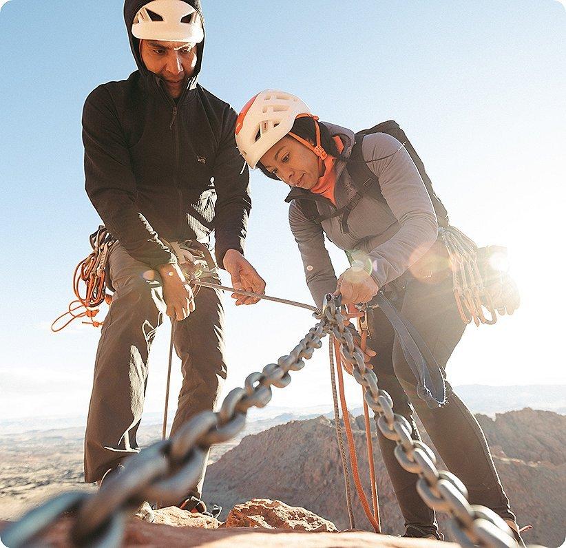 Two climbers tying off the top of their climb