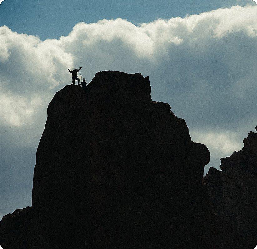 sillhouette of climbers at the top of a ridge