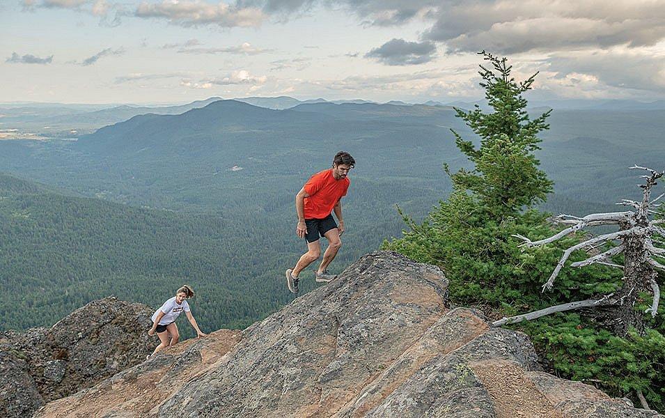 A couple of hikers climbing up a rocky ridge.