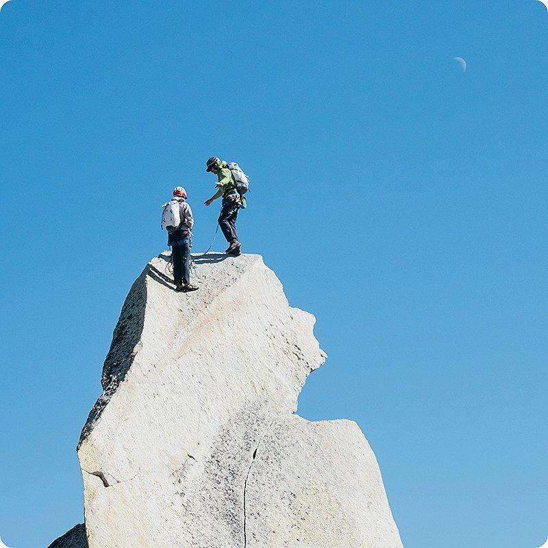 Two climbers tying off the top of their climb