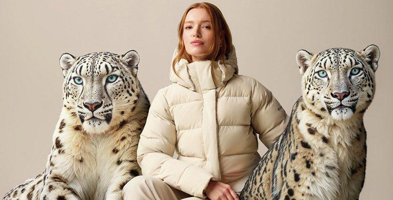 A woman wearing the Amaze Puff coat with two AI generated snow leopards. 