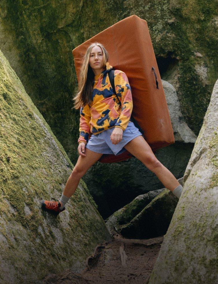 A climber standing on rocks with her crash pad.