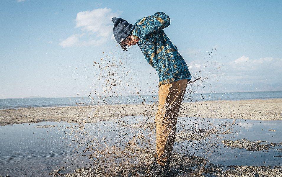 Man jumping in muddy water. 