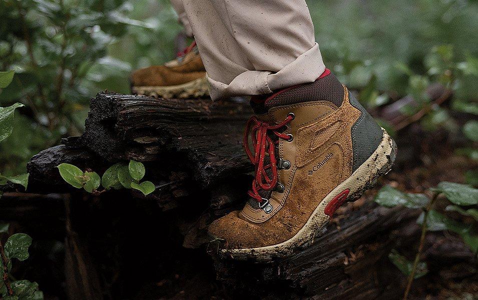 Une personne portant des bottes de randonnée sales Columbia Sportswear marche sur un chemin forestier.