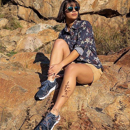 A woman in Columbia hiking shoes sitting on rocks. 