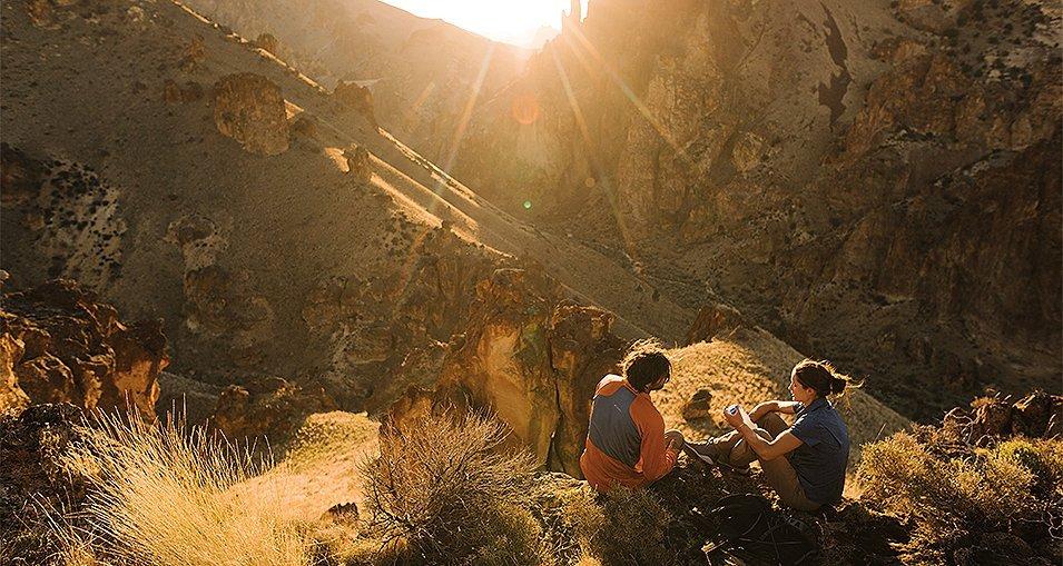 A man and woman taking a break on a late afternoon hike.