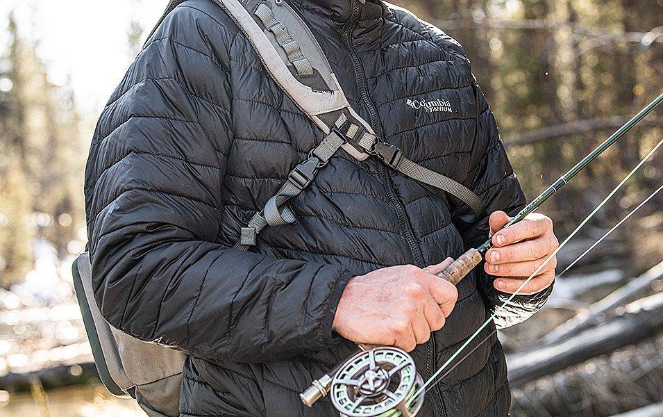 Close-up shot of a fisherman’s hands holding a fly fishing rod. 