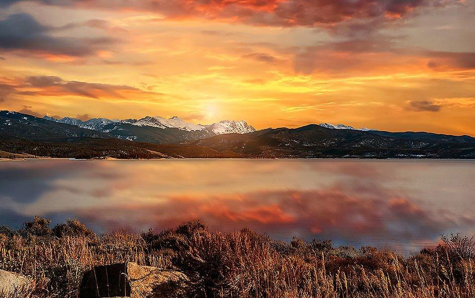 The orange sky is reflected in a beautiful lake at Rocky Mountain National Park in Colorado. 