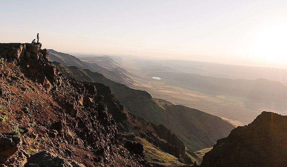 Two hikers on a distant cliff.