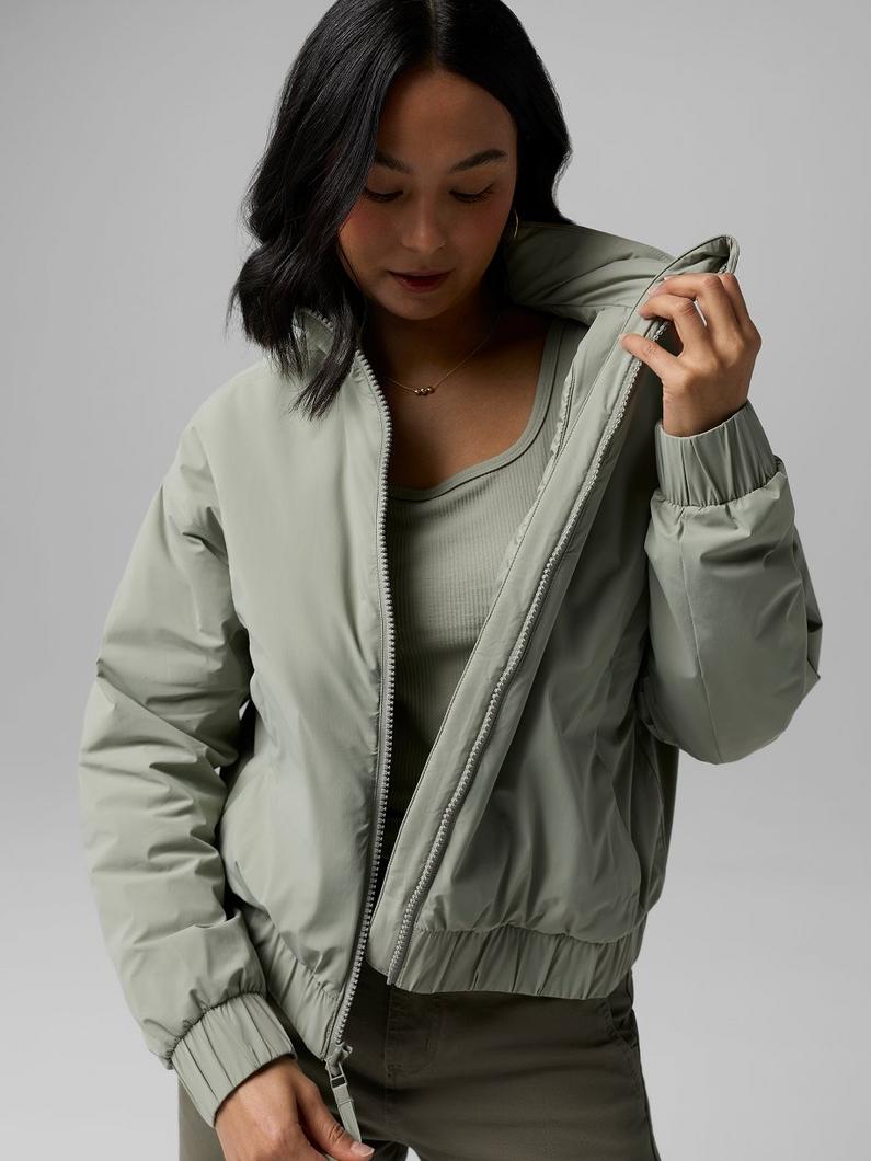 A woman wearing the taupe rain jacket with the hood up.
