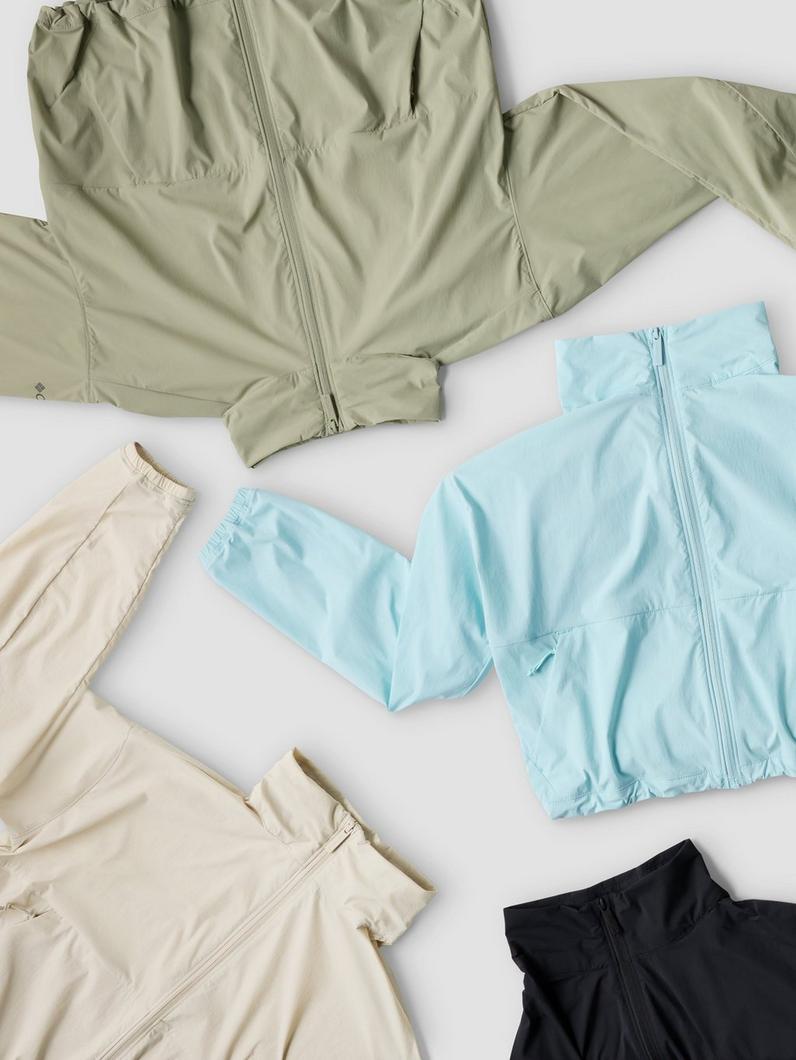 Lightweight zip-up jackets in various colors including sage green, light blue, cream, and black laid flat on a white surface.