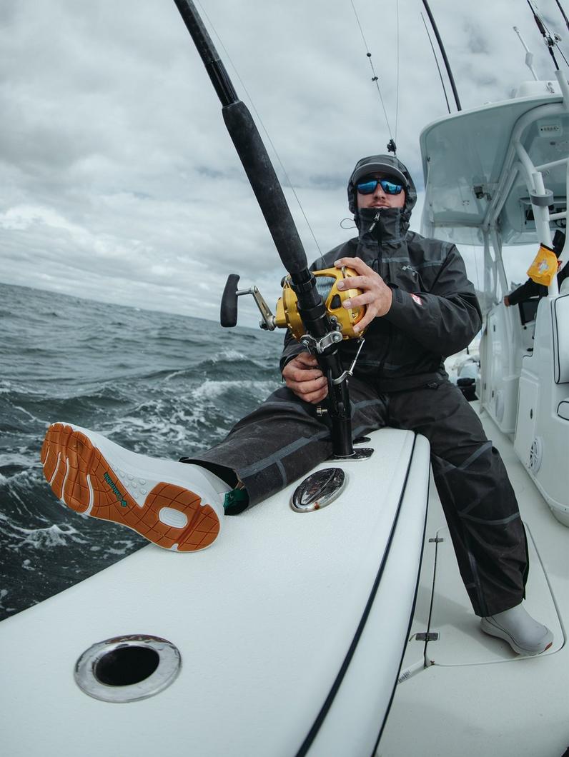 An angler sitting on the side of the boat, wearing Dry Tortugas boots.