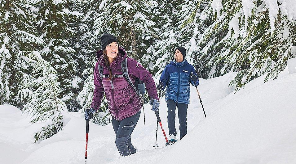 Man and woman snowshoeing in the forest.